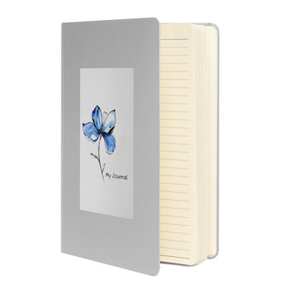 Product mockup of a silver journal with a Blue Butterfly Bean flower on it and the words My Journal. The book is standing up so you can see cream lined pages inside. 